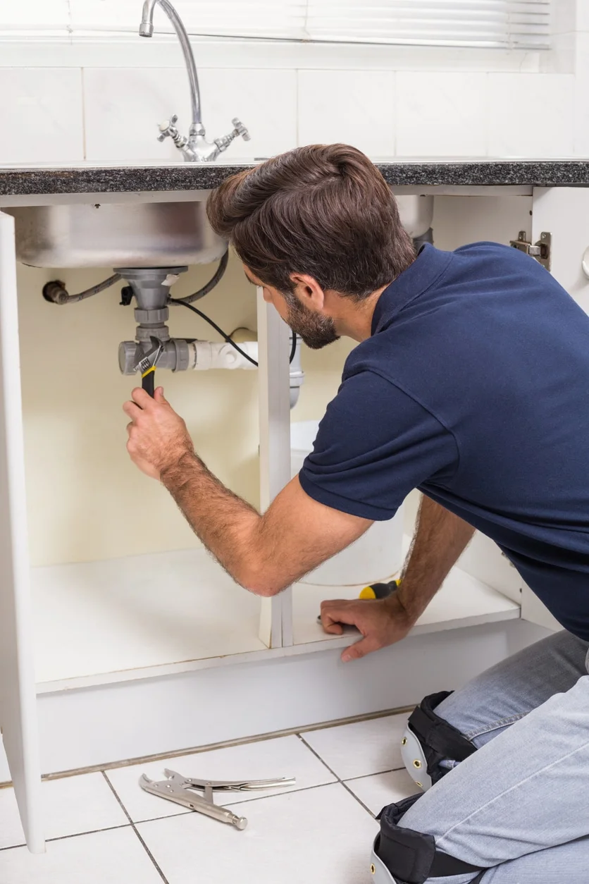 Plumber fixing under the sink drain cleaning calgary